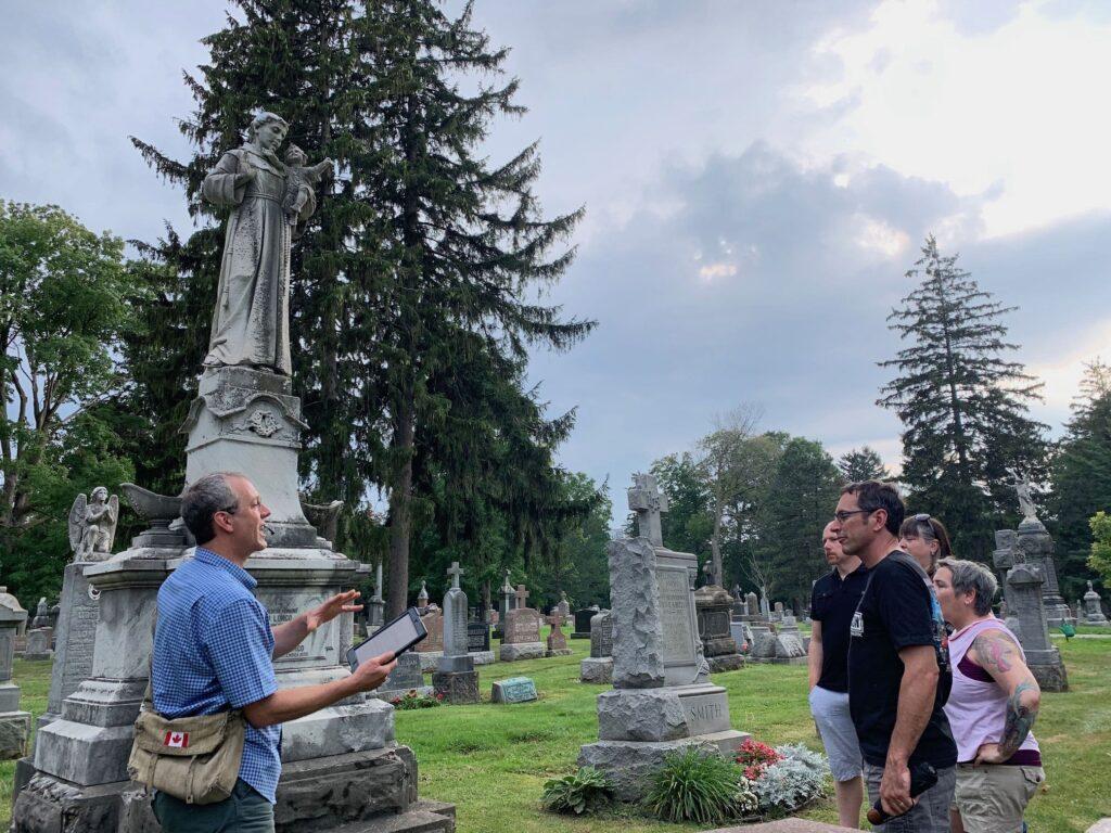 Stroll Walking Tour Guide, Wayne Miedema, leads a tour with four people in Mount Hope Cemetery, Kitchener