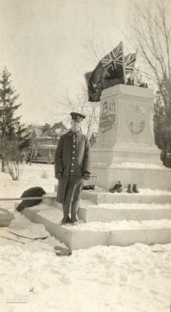 Soldier standing in front of vandalized WWI Kaiser Monument in Victoria Park, Kitchener